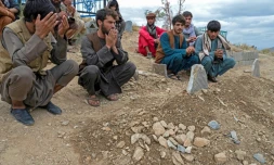 Des Afghans prient devant les tombes des victimes au lendemain d'un attentat à l'explosif dans une mosquée de Kaboul, le 18 août 2022