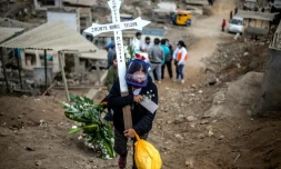 Une femme porte une croix lors des funérailles d'un proche au cimetiÚre de Nueva Esperanza, prÚs de Lima, le 30 mai 2020 au Pérou