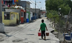 Un garçon porte de l'eau potable chez lui dans le quartier d'Iztapalapa, à Mexico, le 19 avril 2017