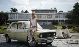 Jovana Stojiljkovic, une des dirigeantes du tour-opérateur Yugotour, assise sur le capot d'une "Zastava 101", devant le musée de la Yougoslavie, le 25 mai 2018 à Belgrade