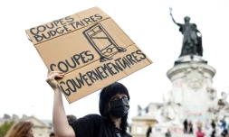 Une manifestante tient une pancarte sur laquelle on peut lire "Coupes budgétaires, coupes gouvernementales" lors d'une manifestation sur la place de la République, à Paris, le 10 septembre 2025