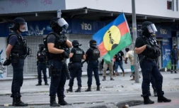 Un drapeau du FLNKS près d'une patrouille des Compagnies républicaines de sécurité (CRS) dans le quartier de La vallée du tir à Nouméa, lors de la fête de la citoyenneté en Nouvelle-Calédonie, le 24 septembre 2024