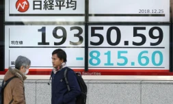 Des piétons passent devant un tableau d'indices boursniers, le 25 décembre 2018 à Tokyo, au Japon