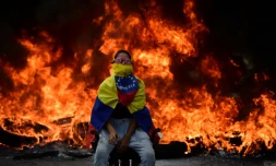 Un manifestant assis devant une barricade en flammes lors d'une manifestation à Caracas, le 24 avril 2017