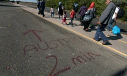Des migrants passent près d'un message "Autriche-2 minutes", écrit au sol à la frontière austro-hongroise, près de Nickelsdorf, du côté autrichien, le 12 septembre 2015 