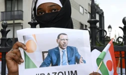 Une femme tient une photo du président nigérien déchu Mohammed Bazoum, détenu depuis le 26 juillet, devant l'ambassade du Niger à Paris le 5 août 2023