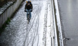 Un homme circule à vélo dans une rue enneigée le 8 janvier 2024 à Mulhouse, dans le Haut-Rhin