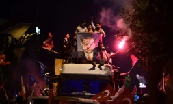 Des partisans du président turc réélu Recep Tayyip Erdogan brandissent des drapeaux turcs et une affiche à son effigie devant le siège du parti AKP, à Istanbul le 24 juin 2018
