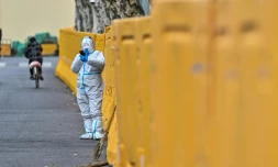 Un homme en tenue de protection devant une barrière érigée à Shanghai, où un confinement a été décrété pour lutter contre l'épidémie de Covid-19, le 31 mars 2022
