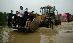 Des habitants évacués à bord d'un véhicule de chantier dans une rue inondée de la localité chinoise de Zhengzhou le 23 juillet 2021