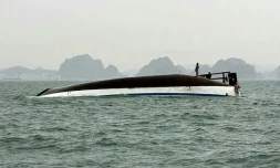 Un homme se tient sur un bateau touristique qui a chaviré dans la baie d'Halong, le 19 juillet 2025
