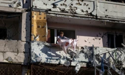 Une habitante nettoie son balcon dans un immeuble résidentiel partiellement détruit par un bombardement, à Kiev le 15 mars 2022