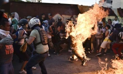 Des manifestants de l'opposition mettent le feu à un voleur présumé pendant une manifestation contre Maduro à Caracas le 20 mai 2017
