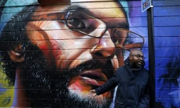 L'artiste britanno-ghanéen Neequaye Dreph Dsane se tient devant l'une de ses oeuvres à Londres, un portrait de l'artiste britanno-marocain Hassan Hajjaj, le 15 janvier 2018