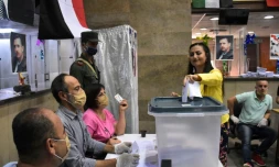 Une femme glisse son bulletin  dans un bureau de vote de la ville d?Alep, dans le nord de la Syrie, le 19 juillet 2020 à l'occasion des législatives syriennes