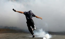 Un manifestant palestinien donne un coup de pied à une grenade lacrymogÚne lors d'afffrontements avec la police à Beit El, prÚs de Ramallah, territoires occupés, le 21 mai 2021