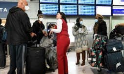 Des passagers portant des masques de protection se renseignent auprès du personnel à l'aéroport de Paris-Charles de Gaulle le 12 mars 2020