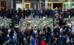 Des personnes se rassemblent devant des fleurs pour rendre hommage aux victimes de l'attentat de Stockholm le 9 avril 2017