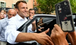 Le prĂ©sident Emmanuel Macron salue la foule aprĂšs s'ĂȘtre entretenu avec le maire de la commune de Bormes-les-Mimosas (Var), le 27 juillet 2019