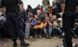 Des policiers croates devant des migrants et réfugiés qui attendent d'entrer dans le centre de transit d'Opatovac en Croatie, le 22 septembre 2015