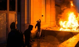 Un homme jette une pierre près d'un véhicule en feu lors d'une manifestation des "gilets jaunes" contre la politique du gouvernement à Paris, le 1er décembre 2018