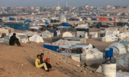 Des enfants palestiniens sont assis non loin d'un camp de fortune oĂč des dĂ©placĂ©s palestiniens ont trouvĂ© refuge le 30 mars 2024