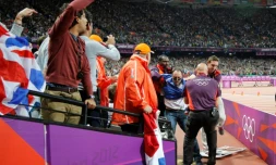 Un agent de sécurité procÚde à l'arrestation d'un spectateur qui a lancé une bouteille sur la piste, avant le départ de la finale du 100 m, le 5 août 2012 aux Jeux olympiques de Londres