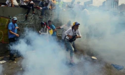 Des manifestants opposés à Nicolas Maduro courent se mettre à l'abri de gaz lacrymogène le 19 avril 2017 à Caracas