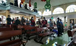 Des fidèles assistent à la messe de Noël, dans leur église encore inondée, le 25 décembre 2021 à Alegria, plus d'une semaine après le passage du typhon Rai aux Philippines