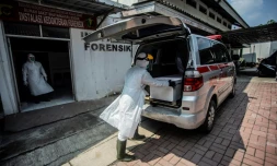 Des soignants installent le cercueil d'une victime du Covid-19 dans une ambulance à Bogor, en Indonésie, le 3 juillet 2021