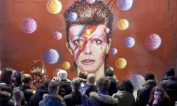 Des fans de David Bowie devant son portrait réalisé par James Cochran, le 11 janvier 2016 à Brixton dans le sud de Londres