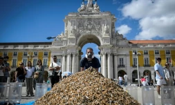 Un militant pour la protection de l'environnement pose devant un tas de mégots de cigarettes entassés sur une place du centre de Lisbonne lors d'une action de sensibilisation contre ce type de pollution, le 23 avril 2023