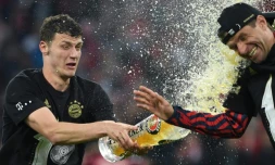Le défenseur français du Bayern Munich Benjamin Pavard arrose de bière l'attaquant Thomas Mueller, après la victoire, 3-1 face au Borussia Dortmund, synonyme de 10e titre de champion consécutif, lors de la 31e journée de Bundesliga, le 23 avril 2022 à l'Allianz Arena