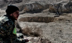 Un membre des milices paramilitaires progouvernementales du Hachd al-Chaabi assis à côté d'un gouffre connu sous le nom de Khasfa, le 26 février 2017 à Athbah, au sud de Mossoul, en Irak