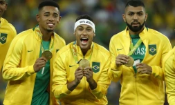 L'international brésilien Neymar au milieu de deux coéquipiers, célèbre la médaille d'or de son pays aux Jeux de Rio, avec un bandeau "100% Jésus", le 20 août 2016 à Rio de Janeiro