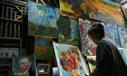 Un artiste peint une copie du tableau "Tournesols" de Vincent Van Gogh dans une allée du village de Dafen, le 19 février 2023 en Chine