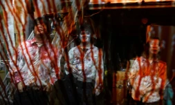 Les acteurs Kota Hanegawa (g), Kenta Iwana (c) et Asami Takeuchi, grimés en zombies, rÎdent devant une voiture dont le pare-brise est couvert de faux sang, lors d'un spectacle de maison hantée en version drive-in, le 15 juin 2020 à Tokyo, au Japon