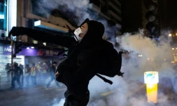 Un manifestant dans un nuage de gaz lacrymogènes tiré par la police, le 25 décembre 2019 à Hong Kong
