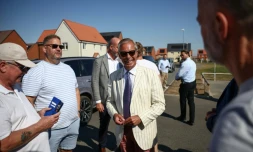 Nigel Farage, (c) chef du parti britannique Reform UK, parle avec des électeurs à la sortie d'un bureau de vote installé dans une école primaire de Walton-on-the-Naze, dans l'Essex, lors de l'élection partielle de Clacton, le 13 août 2026