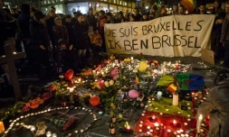 Des personnes rassemblées place de la Bourse à Bruxelles, le 22 mars 2016, devant un parterre de bougies, de fleurs et de messages en hommage aux victimes des attentats