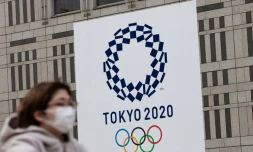 Une femme portant un masque passe devant le logo des Jeux olympiques de Tokyo, le 23 avril 2020