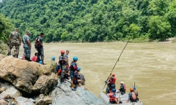 Des membres de la police armée recherchent des survivants dans la riviÚre Trishuli aprÚs un glissement de terrain qui a emporté deux bus, le 13 juillet 2024 à Simaltar, au Népal