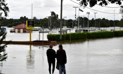 Des résidents regardent la montée des eaux de crue prÚs de la zone commerciale dans la banlieue sud-ouest de Camden à Sydney, le 8 mars 2022