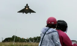 Deux personnes sont assisent sur une moto tandis qu'un avion de chasse de l'armée de l'air taïwanaise s'approche pour atterrir sur une base aérienne à Hsinchu, dans le nord de Taïwan, le 23 mai 2024