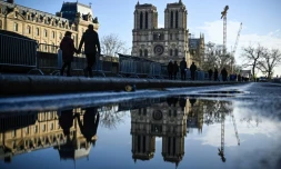 Des piétons longent des barrières de sécurité installées la veille de la réouverture officielle de la cathédrale Notre-Dame de Paris, le 6 décembre 2024 à Paris
