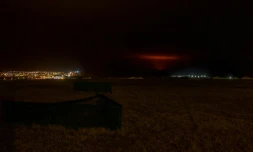 Un nuage rouge du magma lùché par le volcan Fagradalsfjall s'élÚve derriÚre la ville de Keflavik et l'aéroport international, à environ 50 km à l'ouest de la capitale de l'Islande, Reykjavik, le 19 mars 2021