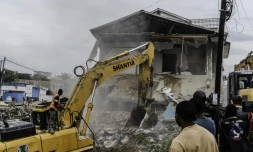 Un engin de chantier démolit des maisons à Kinshasa,, après que les autorités de la RDC ont décidé de démolir tous les bâtiments non autorisés dans les zones inondables, le 8 mai 2025 en RDC