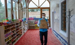 Abdulsamet Cakir, imam de la mosquée Dedeman à Istanbul, porte des cartons de vivres le 21 avril 2020 dans l'entrée de la mosquée