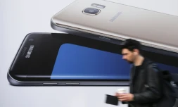 Un homme utilise un smartphone alors qu'il passe devant une publicité pour le Samsung Galaxy S7 à Londres le 11 octobre 2016