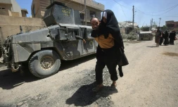Un homme porte une femme sur son dos alors qu'ils fuient les combats entre les forces irakiennes et les jihadistes de l'EI, le 17 mai 2017 à Mossoul-Ouest